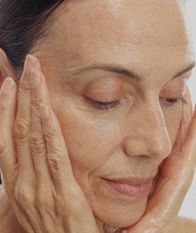 Close-up of a woman's face with hands on her cheeks, focusing on skin texture.